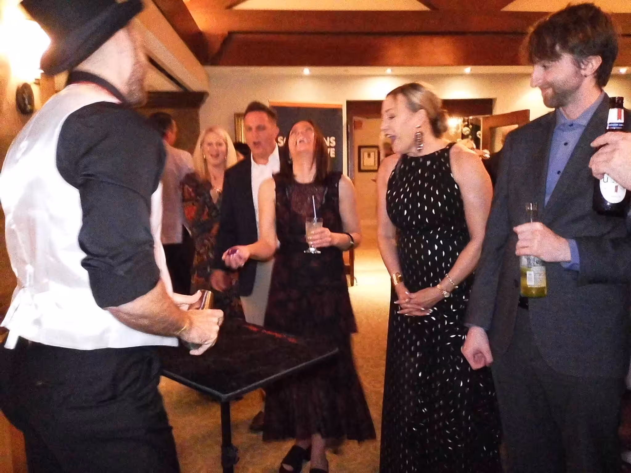 Group of corporate event guests reacting with amazement to a close-up magic trick