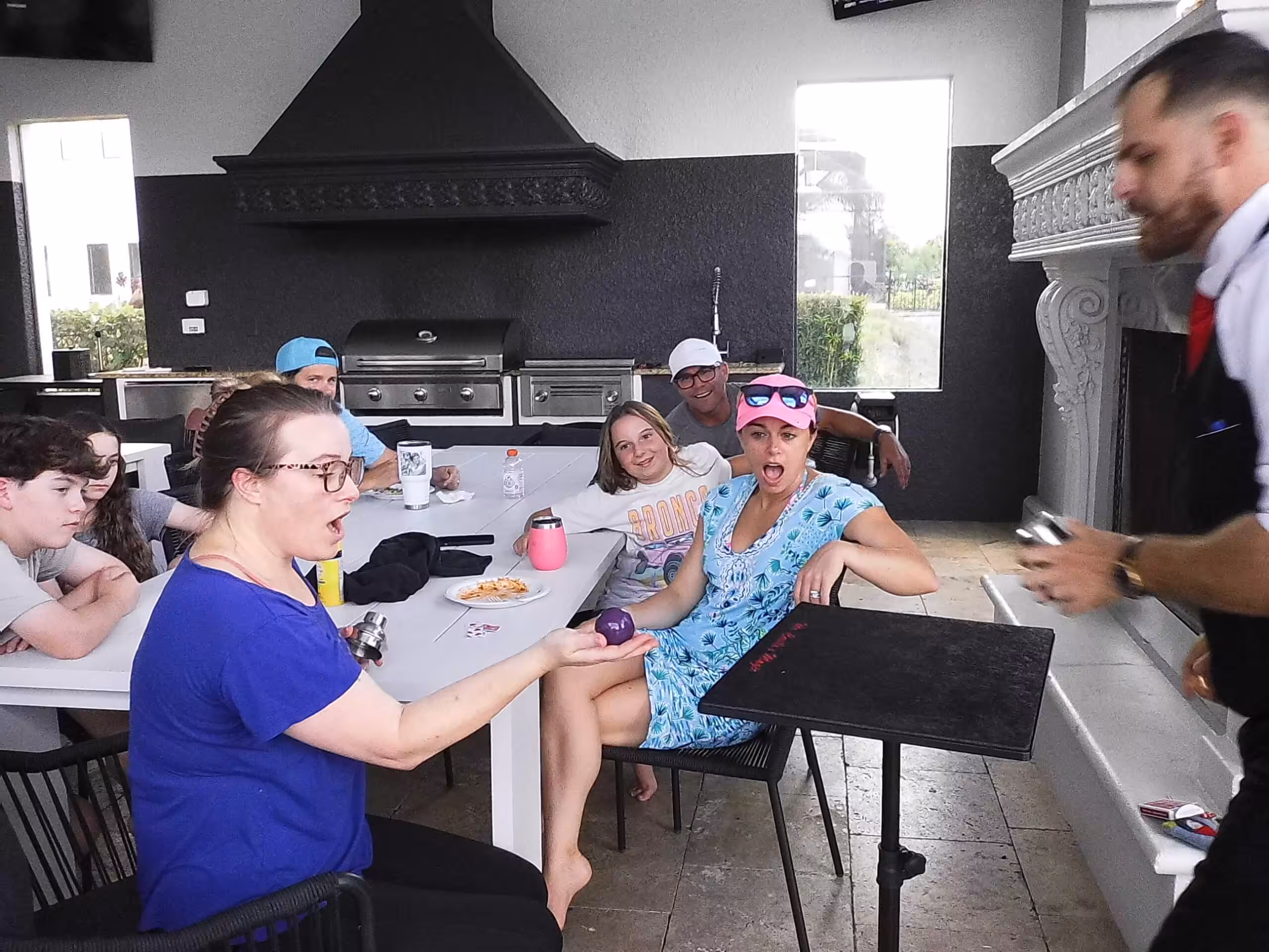 Magician performing close-up magic for a family at a private birthday party with guests reacting in amazement